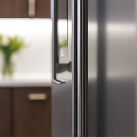 Sub-Zero Integrated Refrigerator Panel Alignment in Sacramento. Technician meticulously adjusting the custom panel of an integrated Sub-Zero refrigerator, ensuring perfect alignment and seamless kitchen aesthetic.
